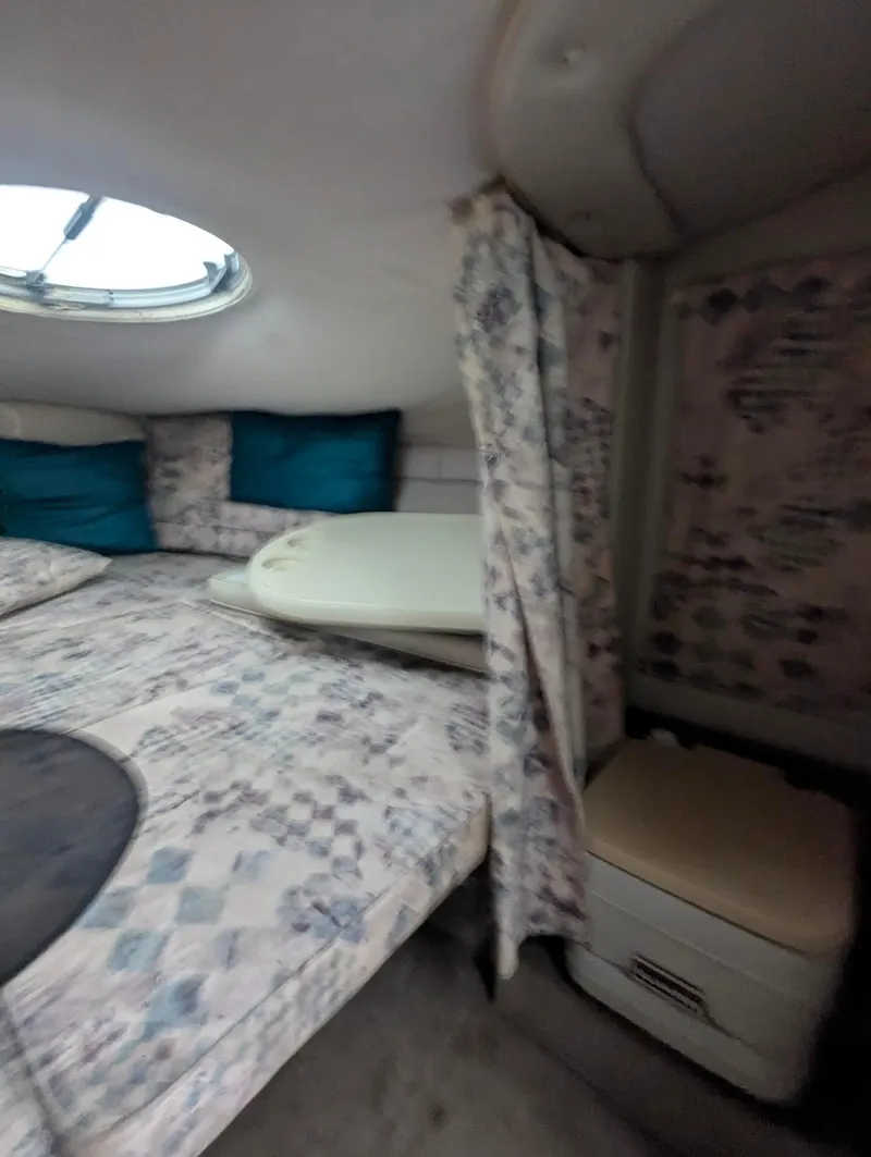Slide: The Image of 1999 Crownline 266 CCR cabin interior with patterned bedding and small window. - 8