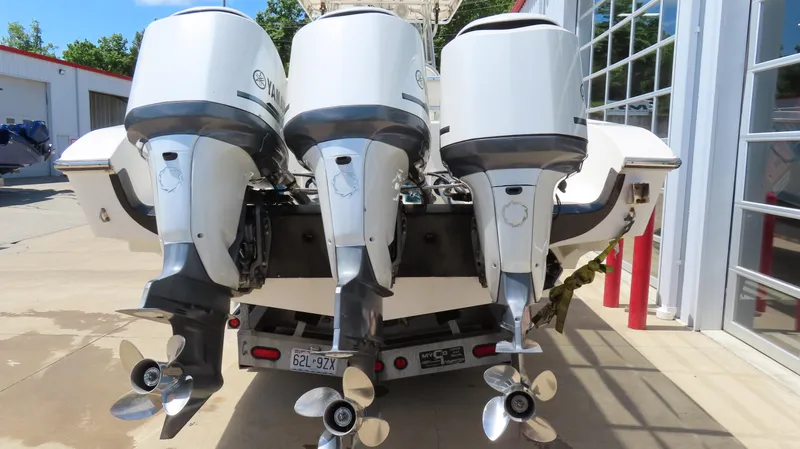 Slide: The Image of Triple outboard motors on a 2002 Fountain 38 TE boat, parked near a garage. - 6