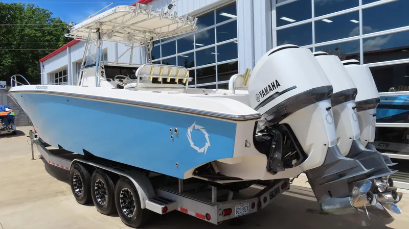 Slide: The Image of 2002 Fountain 38 TE boat with Yamaha engines on a trailer, parked outside a building. - 7