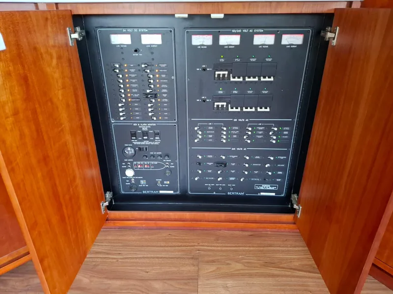 Slide: The Image of Electrical panel inside a 2007 Bertram 630E yacht, with open wooden cabinet doors. - 7