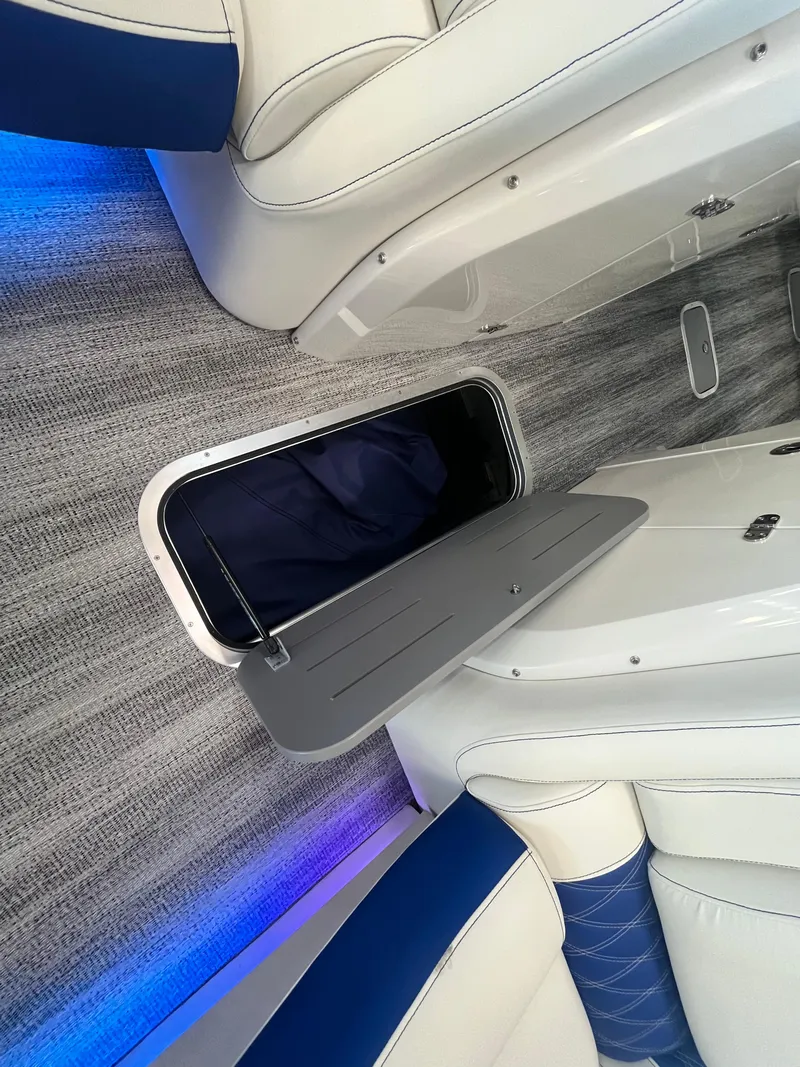 Slide: The Image of 2025 Bennington 27RSBWAT2 boat interior with blue LED lighting and storage compartment. - 13