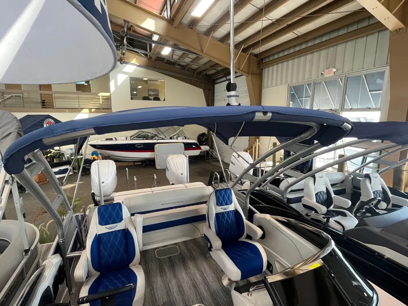 Slide: The Image of 2025 Bennington 27RSBWAT2 pontoon boat with blue and white seating in a showroom. - 18