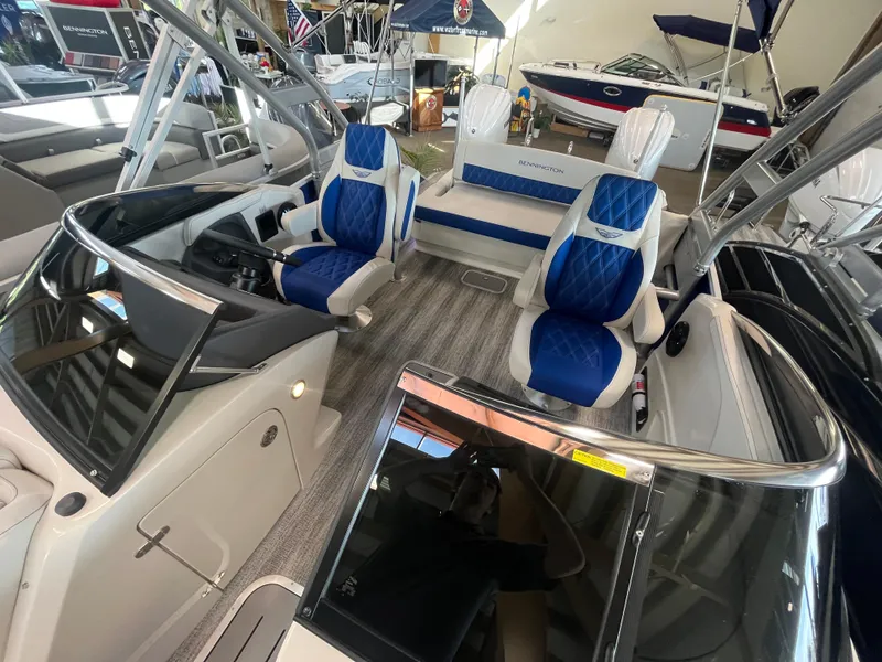 Slide: The Image of 2025 Bennington 27RSBWAT2 boat interior with blue and white seating, showcased at a boat exhibition. - 4