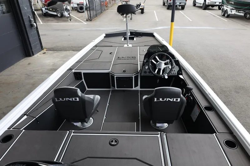 Slide: The Image of 2025 Lund 1875 Renegade SS boat interior with steering wheel and seating in a parking area. - 11