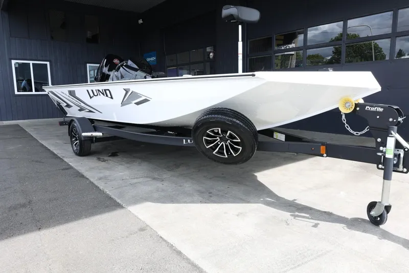 Slide: The Image of 2025 Lund 1875 Renegade SS boat on trailer, parked outside a building. - 2