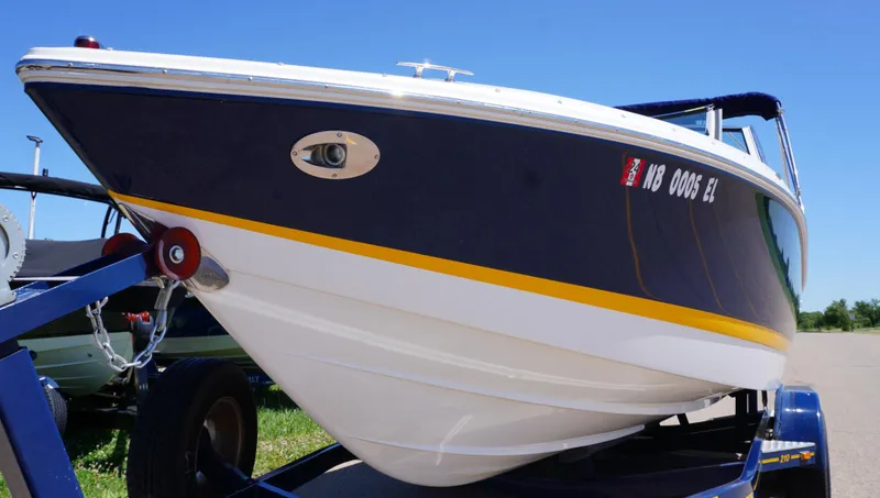 Slide: The Image of 2014 Cobalt 210 boat on trailer, blue and white hull, sunny day. - 2