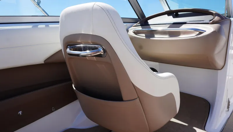 Slide: The Image of 2014 Cobalt 210 boat interior with brown and white seating, steering wheel, and dashboard. - 34