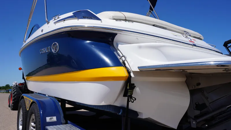 Slide: The Image of 2014 Cobalt 210 boat on trailer, blue and white with yellow stripe, under clear blue sky. - 4