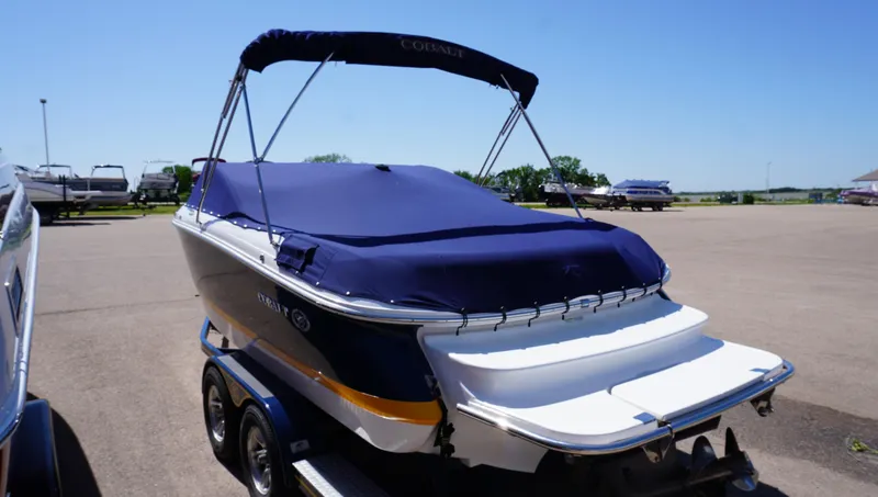 Slide: The Image of 2014 Cobalt 210 boat with blue cover on a trailer in a parking lot. - 45
