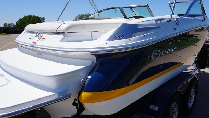 Slide: The Image of 2014 Cobalt 210 boat, white and blue, parked on a trailer, rear view. - 6