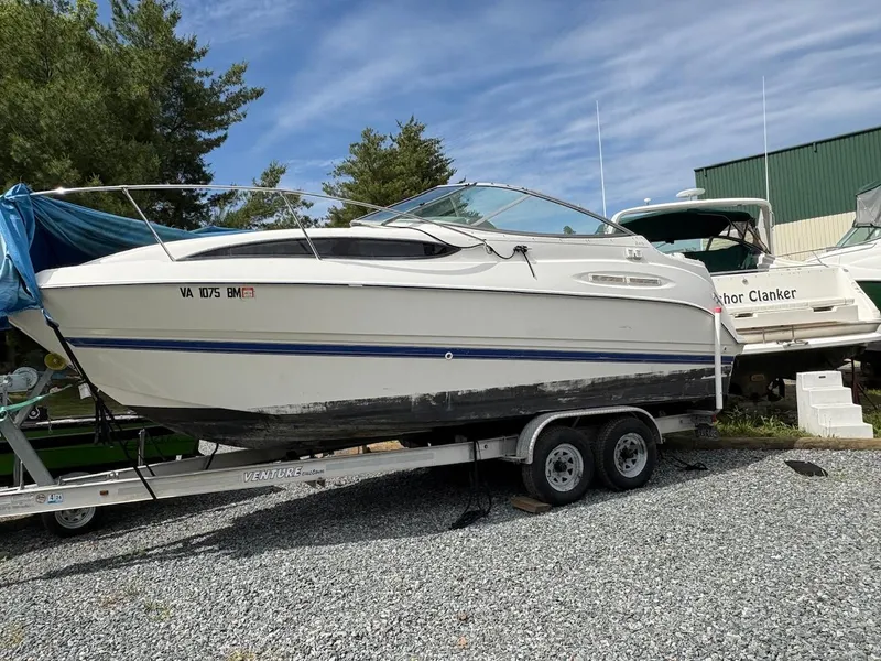 The Image of 2007 Bayliner 245 Cruiser on trailer, parked outdoors on gravel. - 1