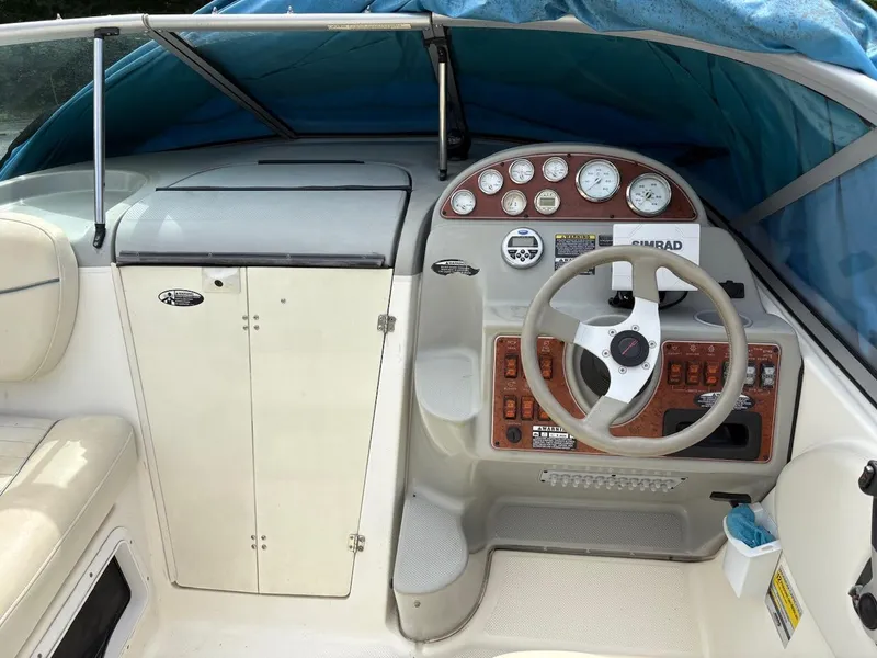 Slide: The Image of 2007 Bayliner 245 Cruiser helm with steering wheel and instrument panel under blue cover. - 14
