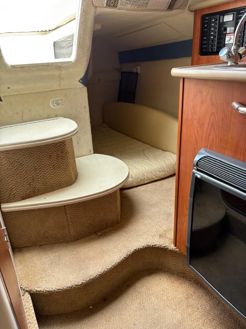 Slide: The Image of 2007 Bayliner 245 Cruiser interior with carpeted steps and compact cabin space. - 7