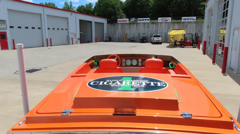 Slide: The Image of Orange 1979 Cigarette 20 boat in a garage lot, showcasing racing team logo. - 19