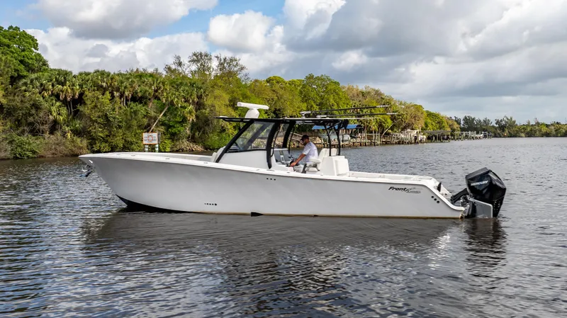 Slide: The Image of 2023 Front Runner 39 Center Console boat on a calm river with lush greenery. - 16