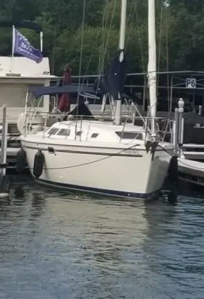 The Image of 1994 Catalina 320 sailboat docked at marina with flag and calm water. - 0