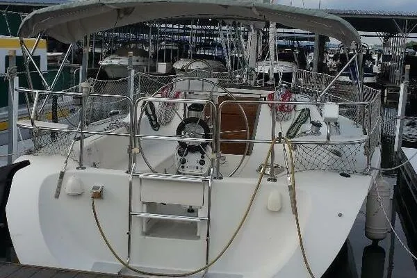 Slide: The Image of 1994 Catalina 320 sailboat docked in marina, featuring spacious cockpit and protective canopy. - 2
