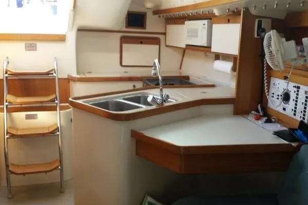 Slide: The Image of Interior of a 1994 Catalina 320 sailboat, featuring a compact kitchen area. - 10