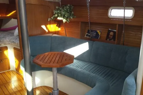 Slide: The Image of Interior of a 1994 Catalina 320 sailboat with blue seating and wooden table. - 9