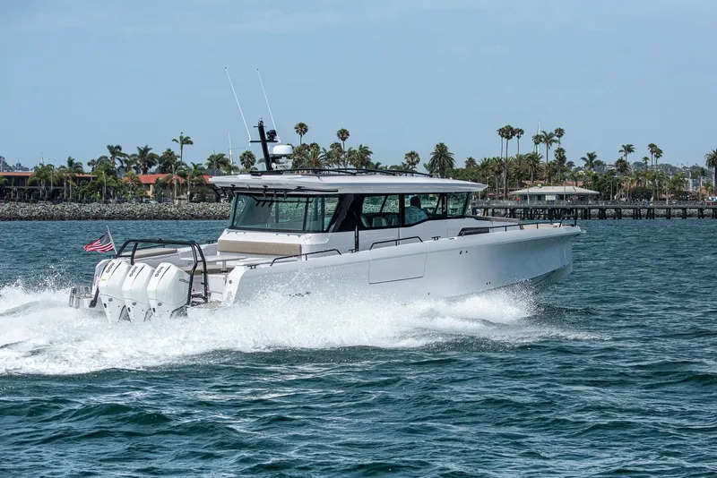 Slide: The Image of 2023 Axopar 45 Cross Cabin boat cruising on water with palm trees in background. - 1