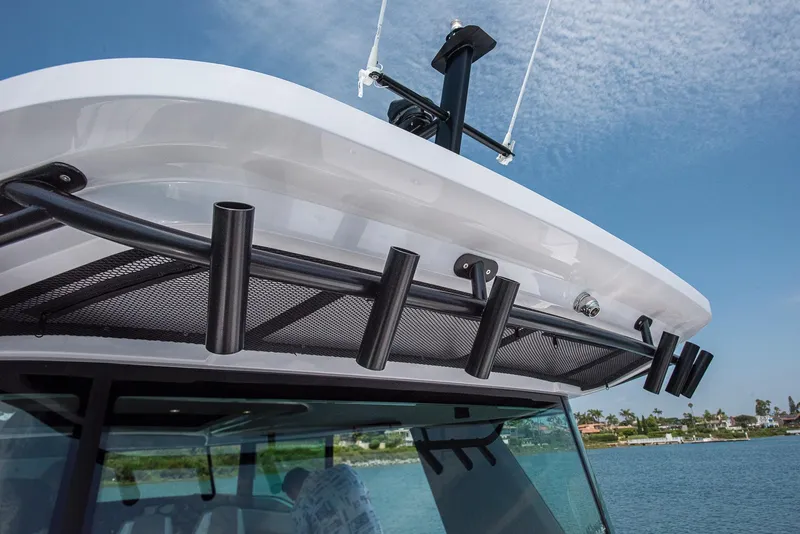 Slide: The Image of 2023 Axopar 45 Cross Cabin boat roof with rod holders, under clear blue sky. - 14