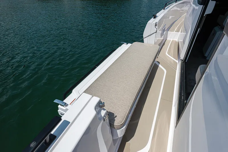 Slide: The Image of 2023 Axopar 45 Cross Cabin boat deck with cushioned seating by the water. - 29