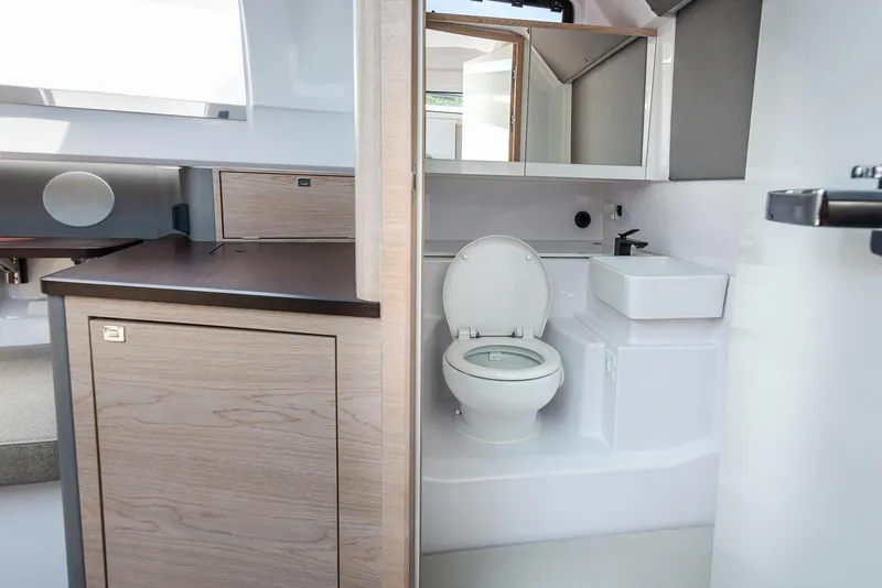Slide: The Image of 2023 Axopar 45 Cross Cabin bathroom with modern fixtures and wood accents. - 34