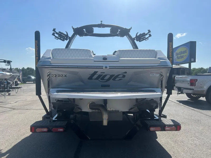 Slide: The Image of 2024 Tigé 22RZX boat rear view in a parking lot under clear skies. - 5