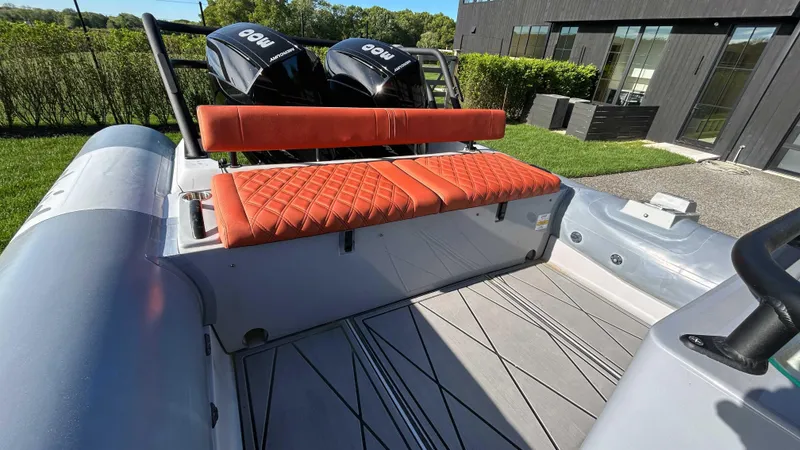 Slide: The Image of 2023 Fluid Watercraft M35 boat with orange seating and dual engines, docked outdoors. - 13