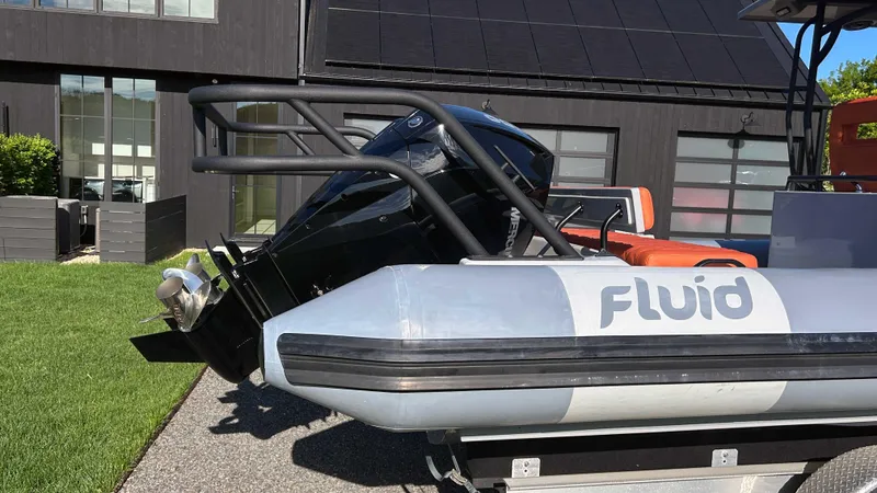 Slide: The Image of 2023 Fluid Watercraft M35 boat with outboard motor, parked on a trailer near a modern building. - 27