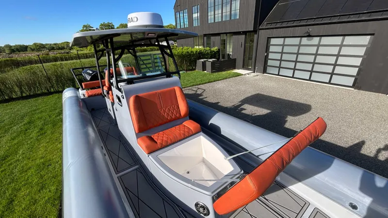 Slide: The Image of 2023 Fluid Watercraft M35 boat with orange seats, parked near a modern house. - 3