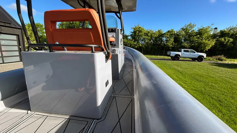 Slide: The Image of 2023 Fluid Watercraft M35 boat with orange seats, parked near a white truck on grass. - 7