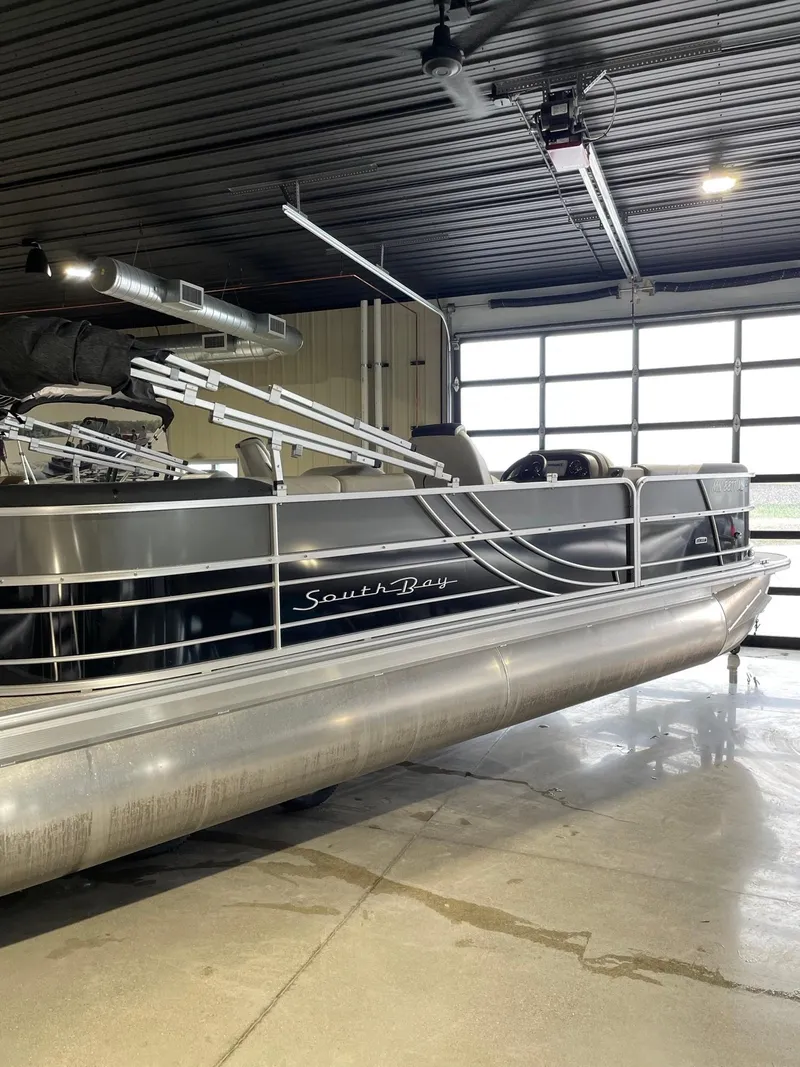 Slide: The Image of 2023 South Bay 224RS LE pontoon boat in a garage setting. - 0
