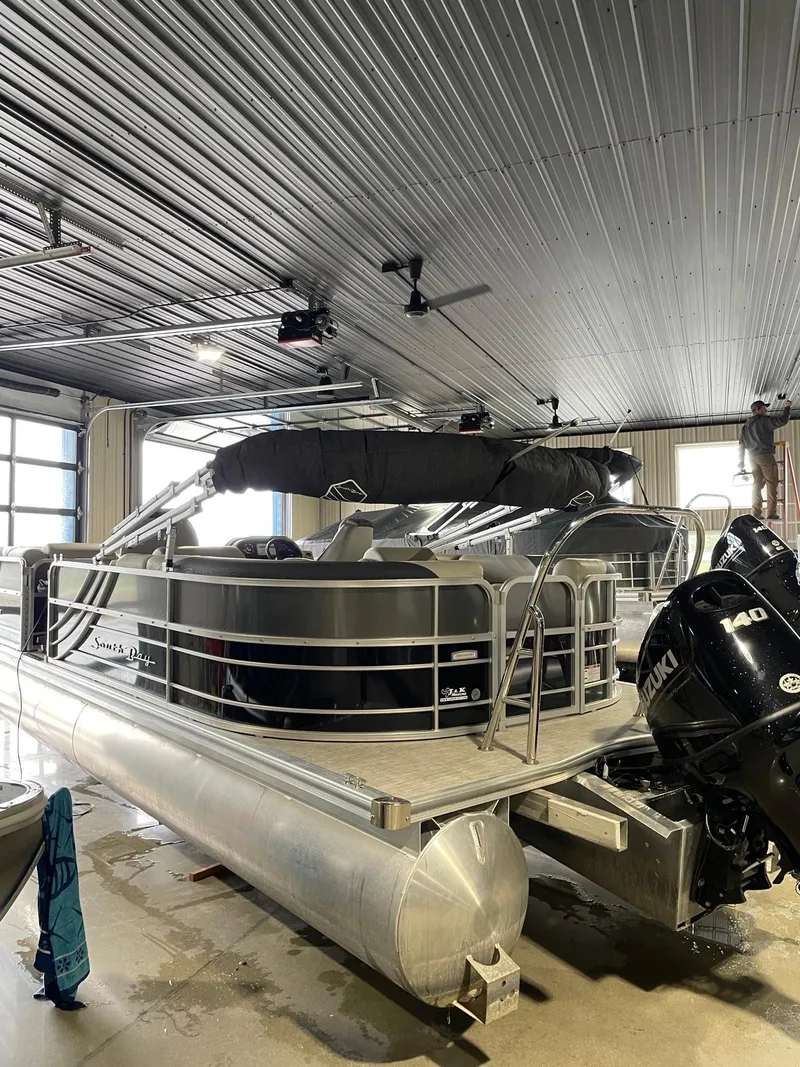Slide: The Image of 2023 South Bay 224RS LE pontoon boat in a garage with Yamaha outboard motor. - 2