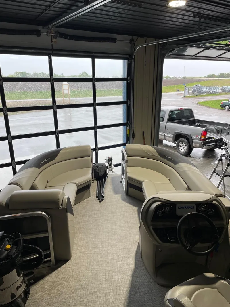 Slide: The Image of 2023 South Bay 224RS LE pontoon boat interior with plush seating in a garage setting. - 7