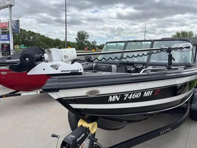 Slide: The Image of 2022 Lund 1975 Tyee Sport boat on trailer, parked outdoors under cloudy sky. - 14