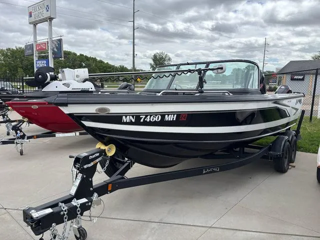 Slide: The Image of 2022 Lund 1975 Tyee Sport boat on trailer, parked outdoors under cloudy sky. - 2