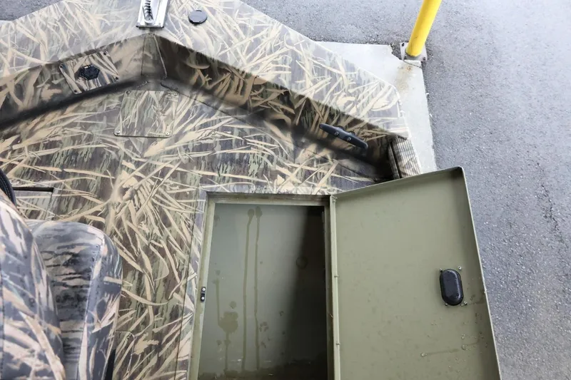 Slide: The Image of 2023 Lowe Roughneck 1760 Pathfinder boat interior with camo design and open storage compartment. - 16