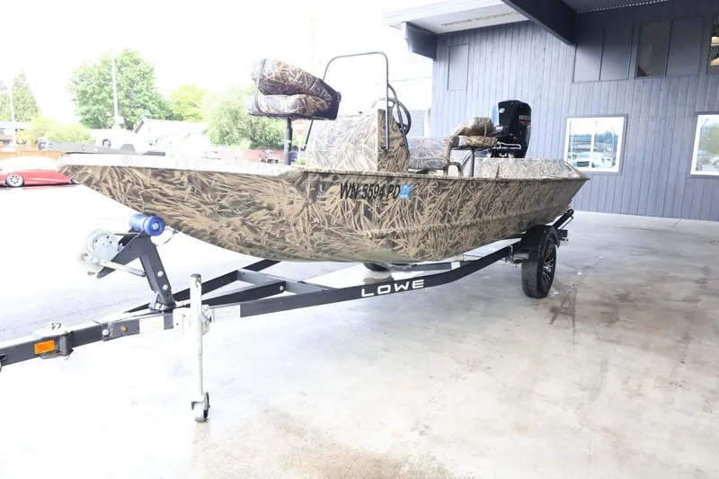 Slide: The Image of 2023 Lowe Roughneck 1760 Pathfinder boat on trailer, camo design, parked outdoors. - 4