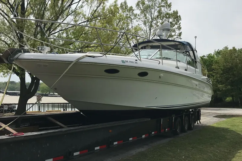Slide: The Image of 1998 Sea Ray 400 Sundancer yacht on trailer, surrounded by trees. - 1