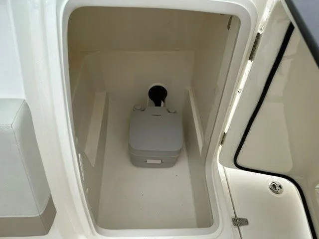 Slide: The Image of 2023 Boston Whaler 240 Vantage boat interior with compact portable toilet. - 13