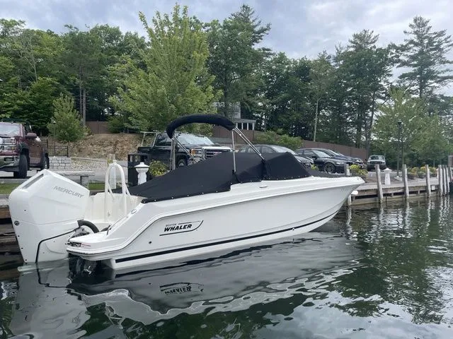 Slide: The Image of 2023 Boston Whaler 240 Vantage boat docked on a calm lake with trees in the background. - 3