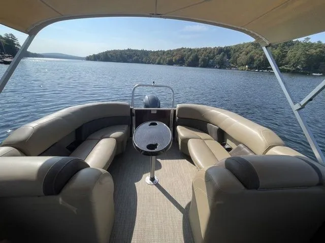 Slide: The Image of 2023 Sylvan 8522 LZ pontoon boat on a serene lake with plush seating. - 4