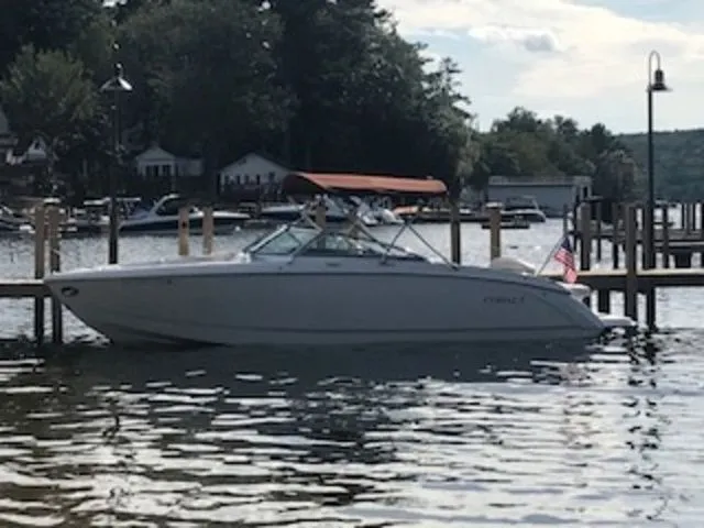 Slide: The Image of 2016 Cobalt R7 boat docked on a serene lake with trees and houses in the background. - 2