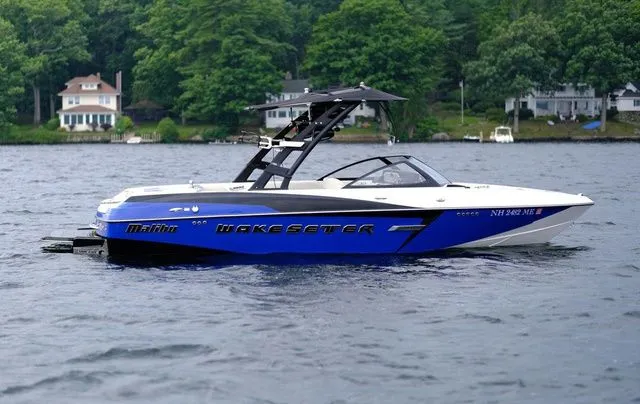 Slide: The Image of 2015 Malibu Wakesetter 22 VLX boat on a lake with lush green shoreline. - 4