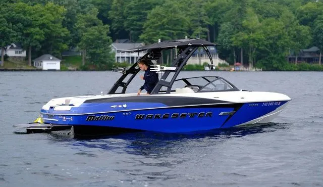 Slide: The Image of 2015 Malibu Wakesetter 22 VLX boat on a lake with lush green shoreline. - 9