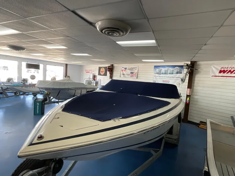 Slide: The Image of 1999 Cobalt 206 boat displayed indoors with blue cover, showroom setting. - 3