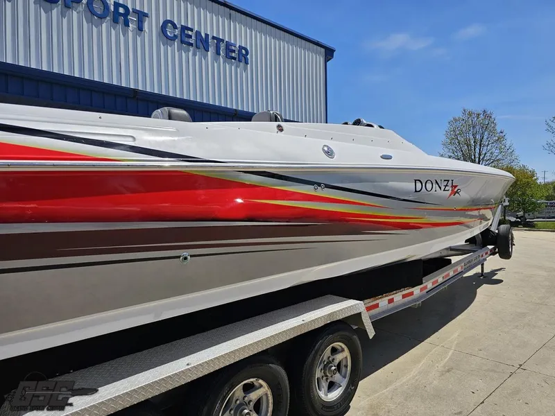 Slide: The Image of 2007 Donzi 38 ZR speedboat on trailer, vibrant red and yellow design, parked near a building. - 12