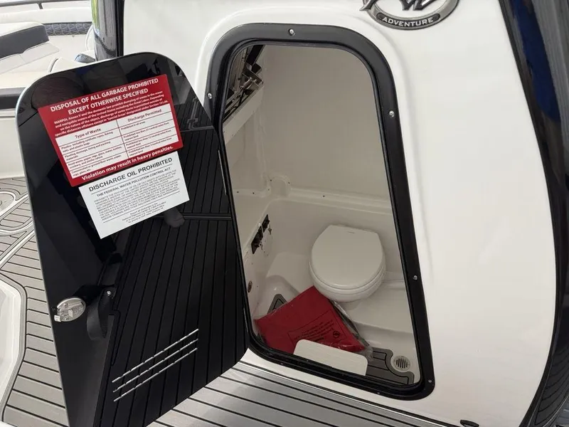 Slide: The Image of 2025 Tidewater 282 CC Adventure boat interior with open door revealing compact marine toilet. - 13
