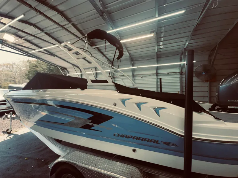 Slide: The Image of 2023 Chaparral 21 SSi OB boat in a garage, featuring sleek blue and white design. - 1